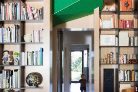 Large bookshelves and wooden walls separate spaces inside the Doll's House