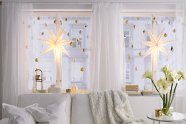 Large bright star lights hung with smaller ornaments in window