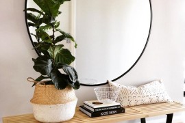 Large round mirror above a wood bench
