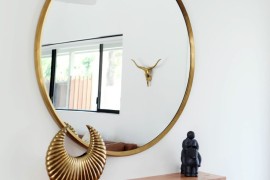 Minimal entryway decor with a large round mirror with gold frame