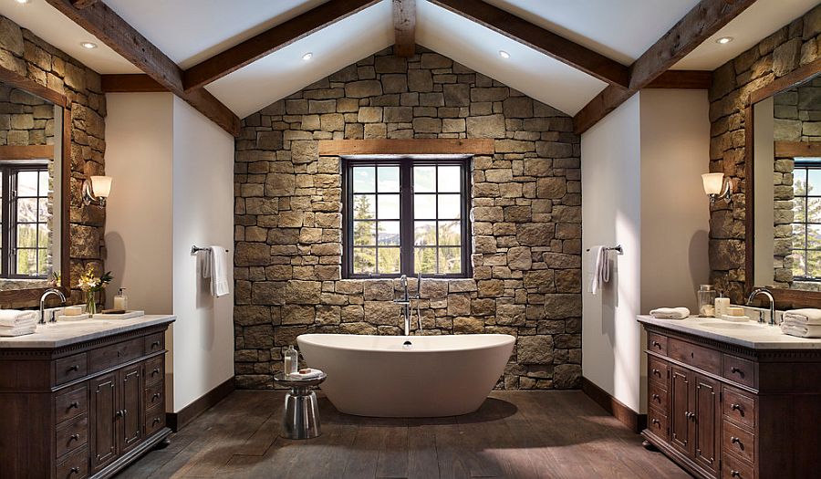 Rough cut stone wall and wooden ceiling beams create a cozy ambiance in the bathroom
