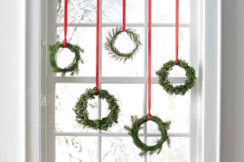 Tiny wreaths hung with red ribbon in a window