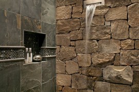 Waterfall shower head is a perfect fit for the fabulous stone wall in the bathroom
