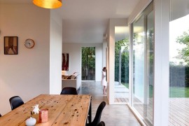 Wooden dining table and black chairs create a room within the kitchen with ease