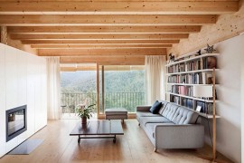 Sliding glass dooes with wooden frames and sheer curtains open up the living room to the view outside