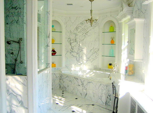 A marble bathroom with a perfume bottle display