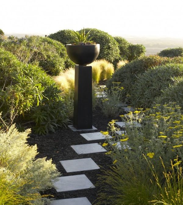 Beautiful pathway of stones and a gorgeous plinth with a bowl on top standout in this garden