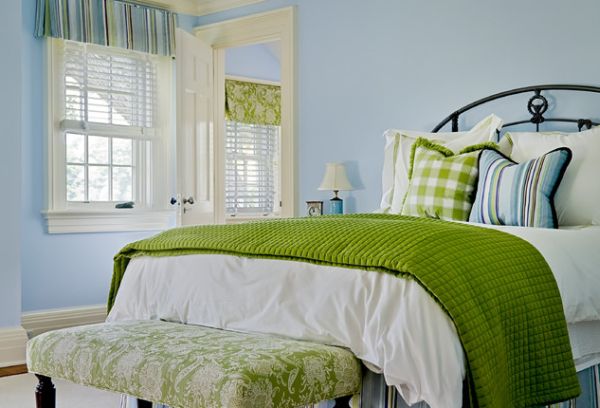 Bedroom in green sports a bench with fabric similar to one use for a Roman shade in the room