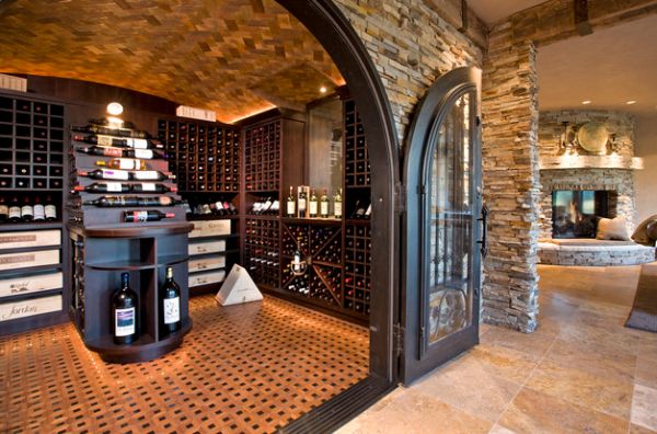 Large archway with iron doors and wooden flooring give this wine storage space a traditional look