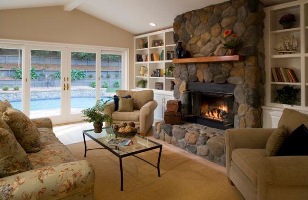 Well ventilated living room with a stone fireplace that sports daft glass doors