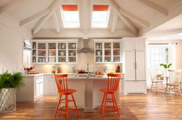 Airy white kitchen employs skylights with orange blinds along with chairs in similar hue