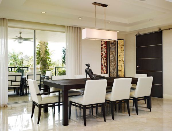 Modern dining area and patio connected with sliding glass doors hidden behind white curtains