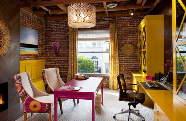 Home office sports exposed brick walls along with shades of fuchsia and yellow