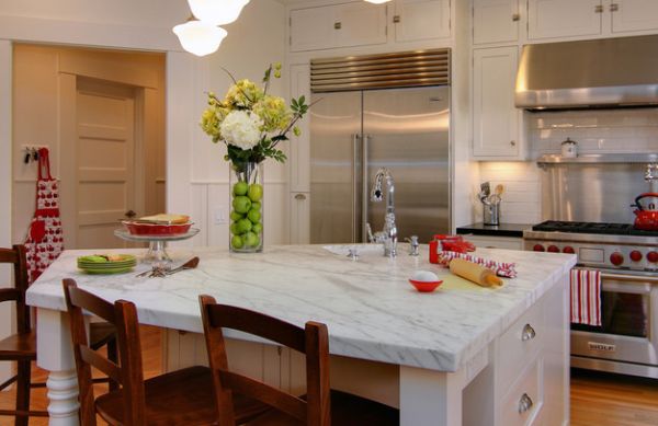 A fruit and flower arrangement that is on a marble kitchen countertop.