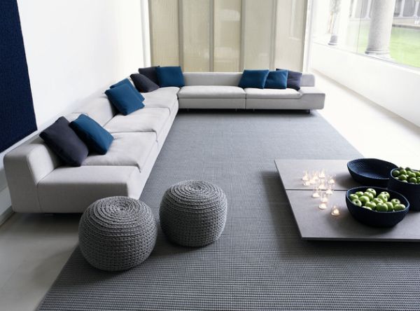 Three large fruit bowls, two of which are full of green apples in a modern living room.