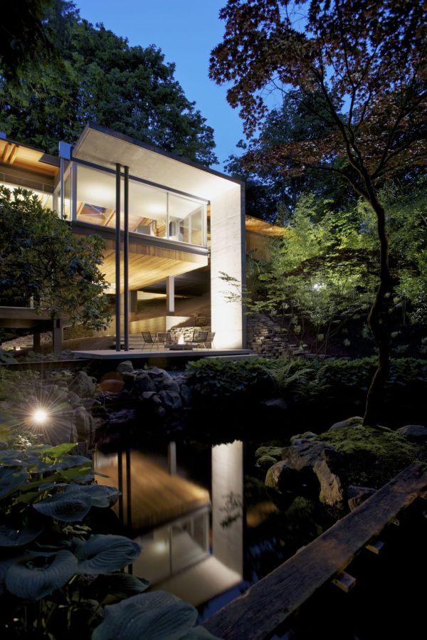 Modern house surrounded by lush green vegetation and maple trees