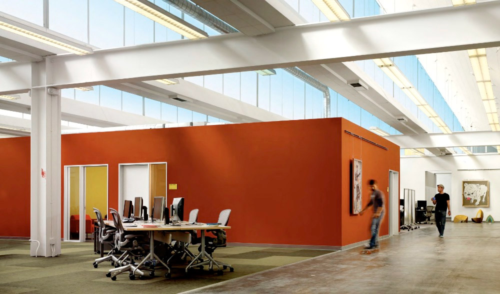 Bright orange conference room structure sits in the middle of an open area via bustler