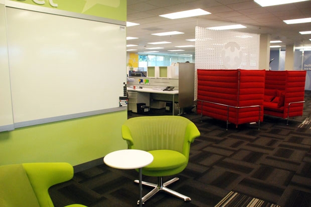 Green open meeting area with red comfy cubes in the background