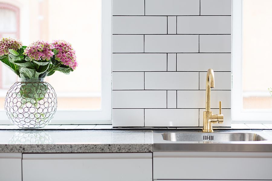 Brass sink faucet with a lovely flower vase next to it