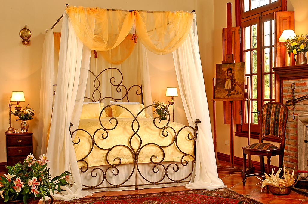 Delazious wrought iron canopy bed with yellow and white drapery and bedding