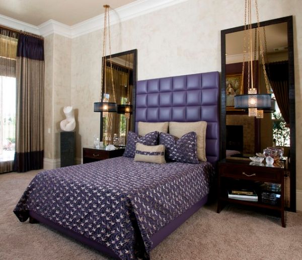 Purple headboard and brilliant chandeliers shape an opulent bedroom