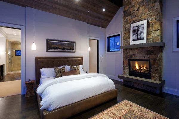 Wooden ceiling and stone fireplace give the bedroom a luxury cabin appeal