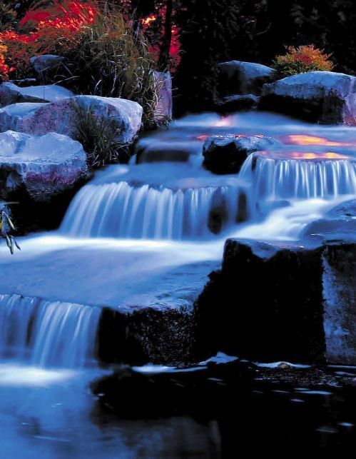 dramatic lighting of water feature in garden