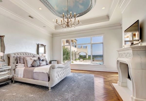 Carved marble fireplace and tufted sleigh bed bring opulence to the bedroom