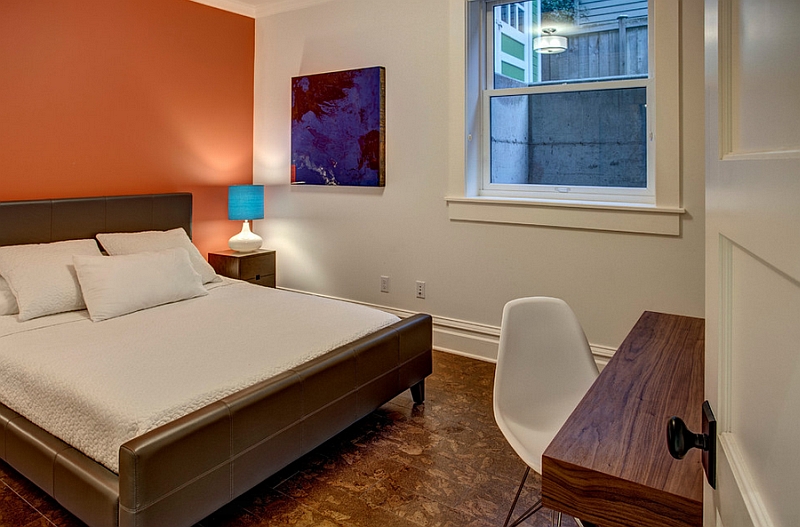 Bright orange accent wall enlivens the bedroom