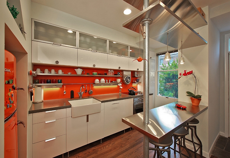 Bright orange backsplash in the compact kitchen