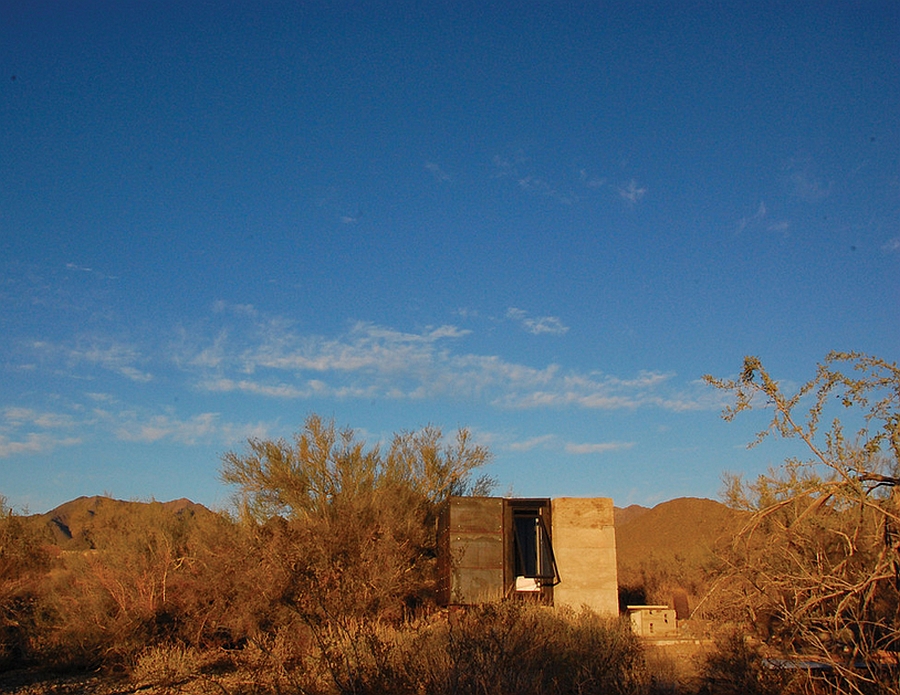 Glass and concrete tiny shelter blends into the backdrop