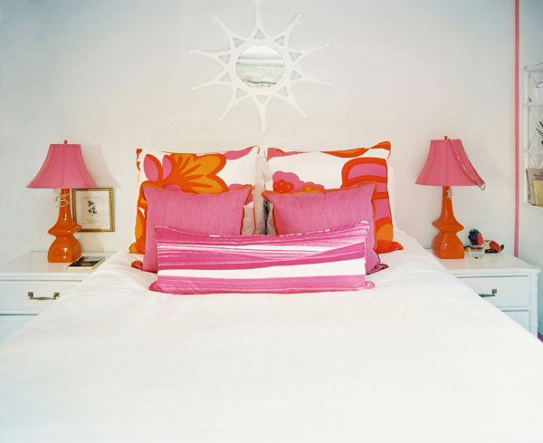 Orange and pink wake up this all-white master bedroom