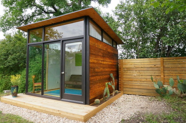 A tiny house next to a cedar fence