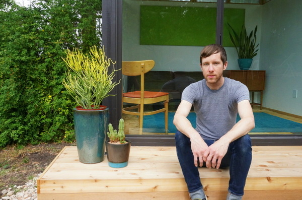 Andy Pluta in front of the tiny house he built in his backyard