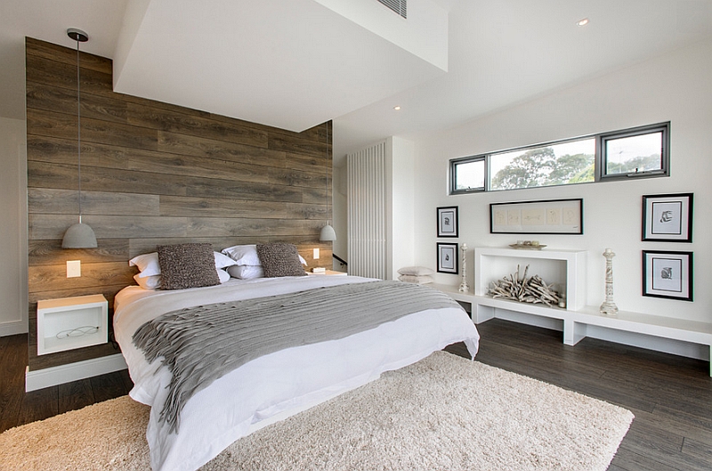 Bedside pendants and accent oak wall accentuate the minimal appeal of the room