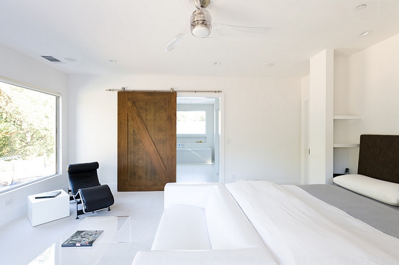 Use of barn door adds warmth to the minimalist room in white