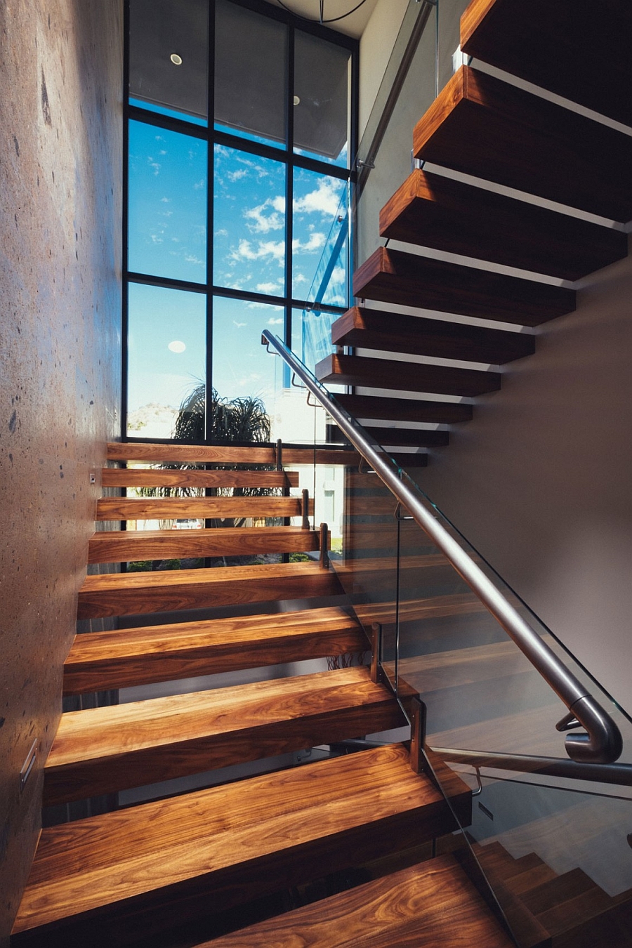 Floating wooden stairs with a glass and steel railing