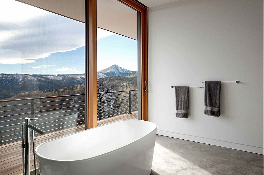 Freestanding bathtub in white offers sweeping views of the mountain range outside