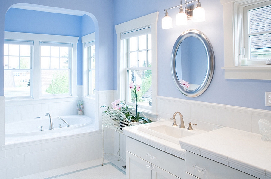 Gorgeous bathroom in blue and white with round mirror above the sink