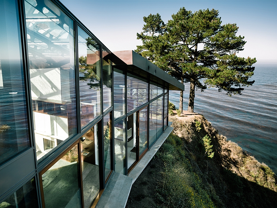 Large glass windows on the side of the contemporary home atop a cliff