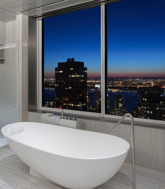 Standalone bathtub placed next to the window with city skyline views