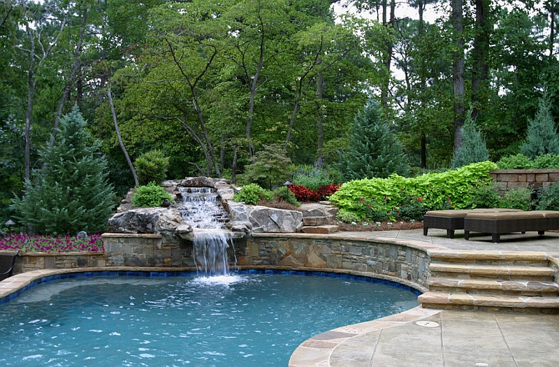 Raised patio features a stone waterfall that leads into a pool