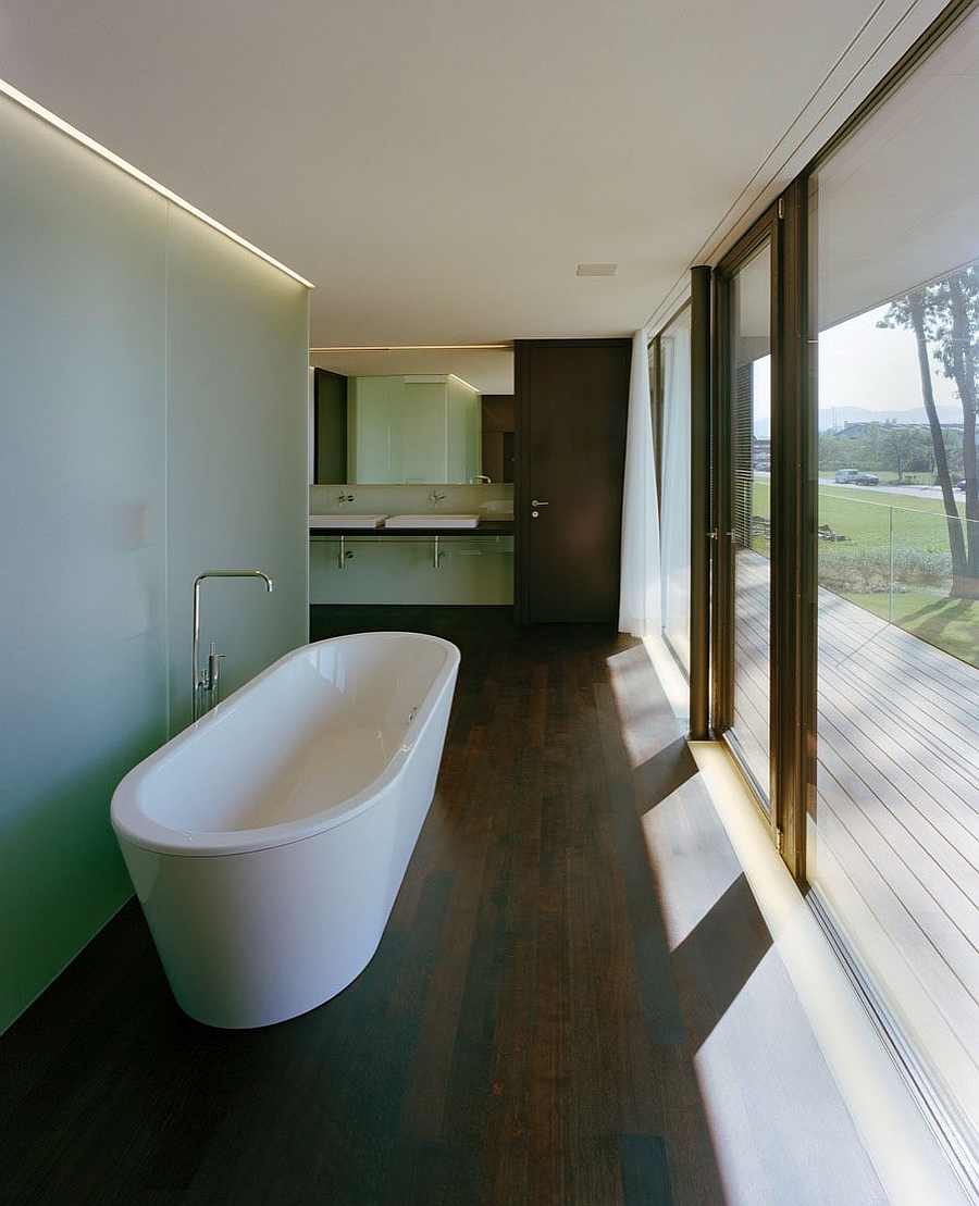 Standalone bathtub in white next to the glass shower area in frosted glass