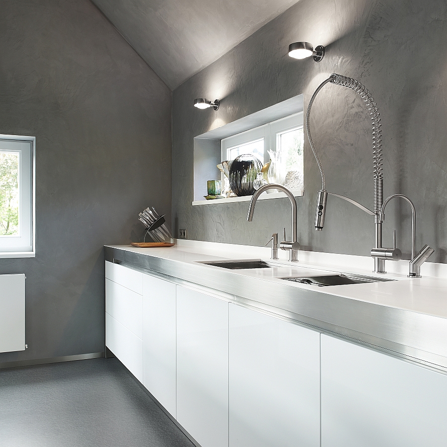 The unfinished concrete backdrop elevates the appeal of the kitchen faucet