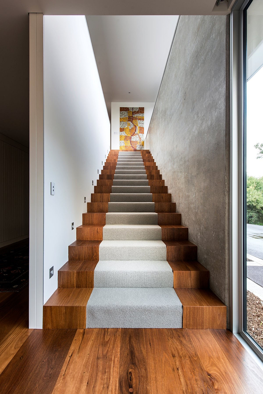 Wooden staircase flanked by concrete walls leads to the top level