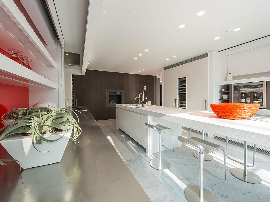 Expansive kitchen island, stainless steel countertops and wooden accent wall shape the stylish kitchen