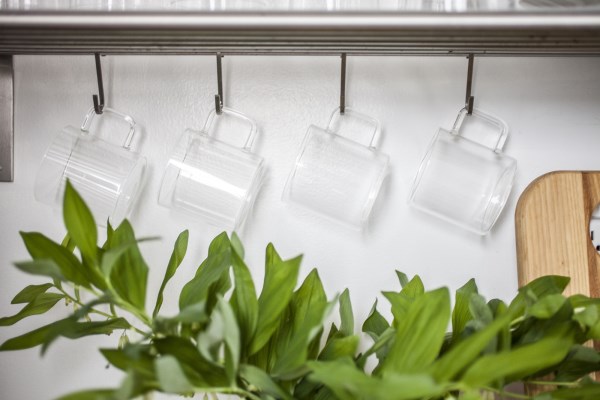 Mugs hang from a stainless steel shelf