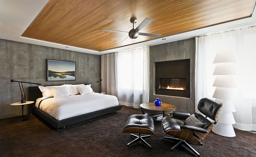 Natural eucalyptus ceiling in the bedroom with exposed concrete walls and the iconic Eames Lounger