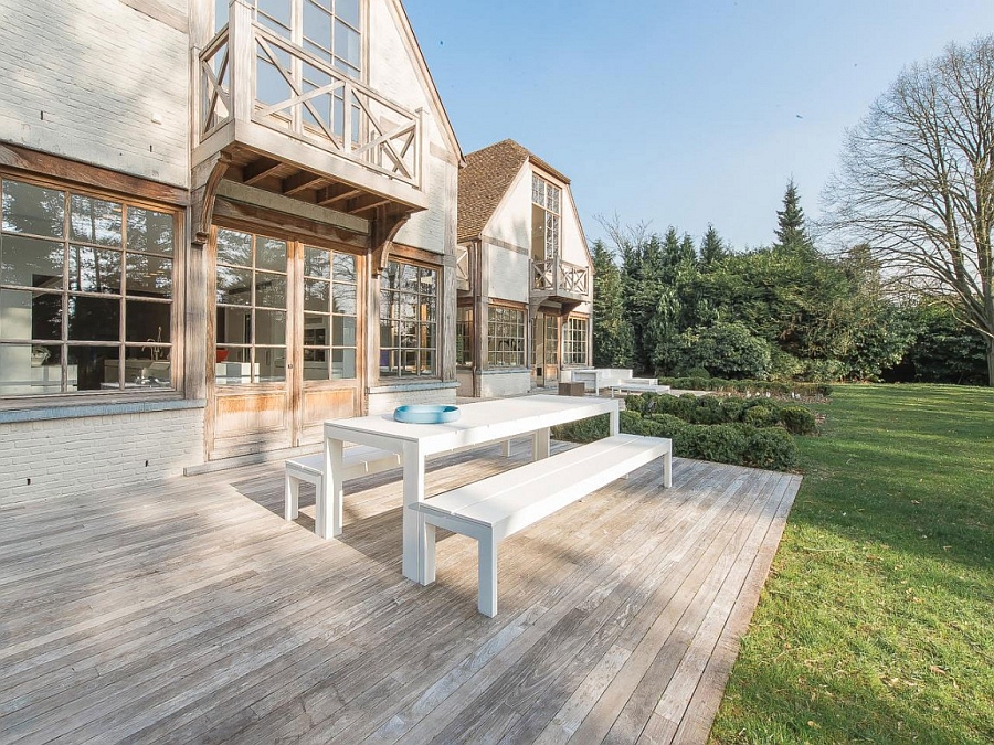 Outdoor wooden deck with cool dining space extending into the lavish backyard