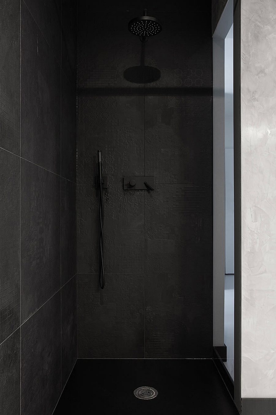 Stylish shower area clad in black tiles